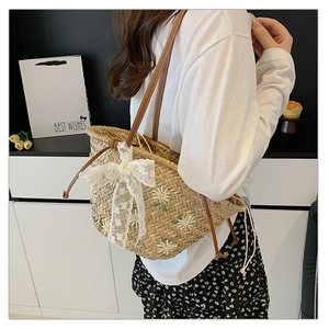 Detail of straw bucket bag with floral embroidery and white lace bow decoration