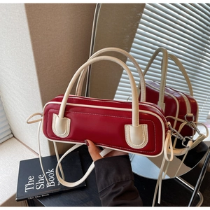 Detail of red cylindrical Boston bag with beige piping and silver zipper hardware