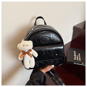 Detail of vintage black patent leather mini backpack with bear charm and embossed logo