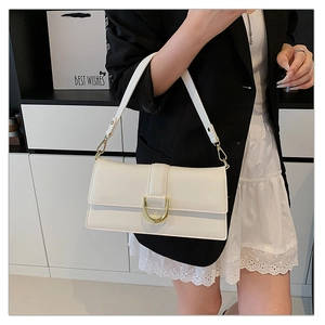 Gros plan du sac sous le bras en cuir blanc avec boucle en U dorée porté par un mannequin