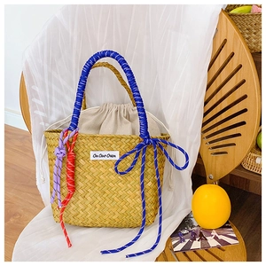 Detail of hand-woven straw bucket bag with colorful rope handles and inner drawstring pouch