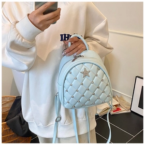 Detail of light blue quilted mini backpack with silver rivets and rhinestone star charm