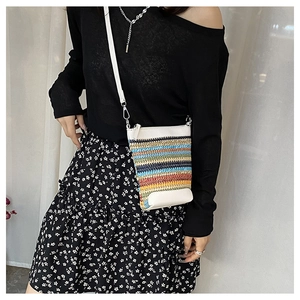 Rainbow striped woven crossbody phone bag with white leather trim styled on a model