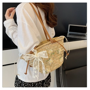 Detail of straw bucket bag featuring white daisy embroidery and lace bow decoration