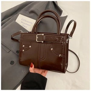 Gros plan détaillé d'un sac en cuir verni marron foncé avec rivets et boucles de ceinture