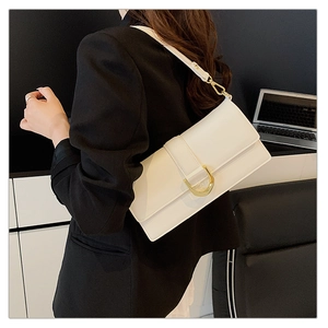 Détail du sac à bandoulière en cuir blanc avec une boucle dorée distinctive en forme de D