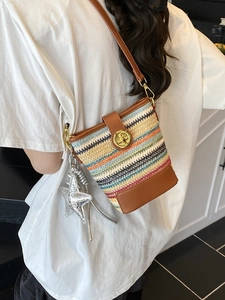 Colorful woven bucket bag with leather base and star charm shown on a white T-shirt