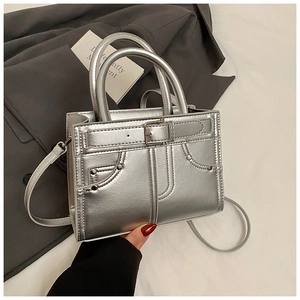 Détail du sac à main argenté métallisé avec boucles cloutées et finition nacrée
