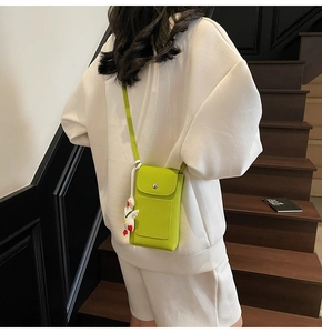 Detail of lime green litchi texture crossbody phone bag with cute white duck charm