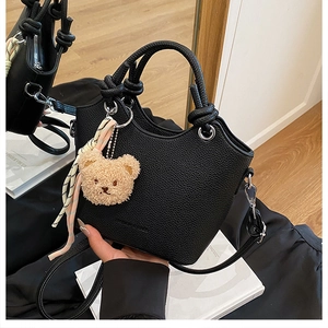 Detail of black pebbled leather bucket bag with knotted handle and silver ring accents