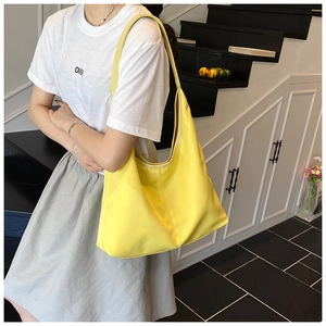 Close-up of bright yellow large capacity hobo shoulder bag worn on the model's shoulder