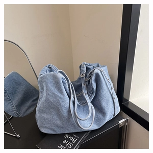 Detail view of washed denim tote bag with metal eyelets on the shoulder strap