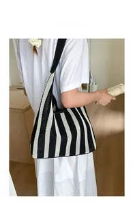 Detail of black and white striped knitted hobo bag with wide shoulder strap on a model