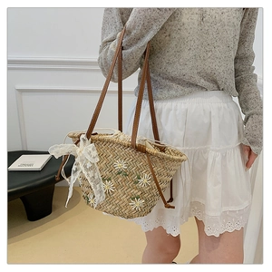 Detail of summer straw bucket bag featuring daisy embroidery and a white lace bow accent