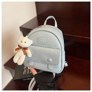 Detail of light blue mini backpack with crinkled PU leather texture and cute bear charm