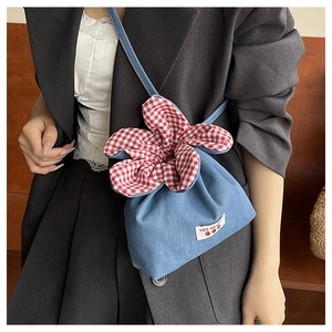 Detail of blue denim crossbody bag with red gingham flower and strawberry patch