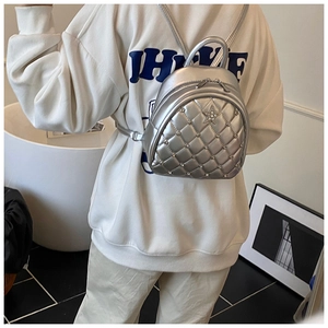 Silver quilted mini backpack with star logo and round metal studs in a lifestyle setting