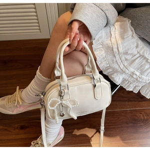 Detail view of off-white faux leather Boston bag with pearl bow and heart charms