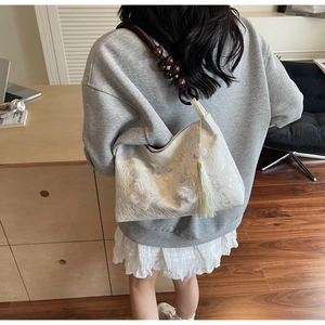 Détail du sac en dentelle blanche avec broderie papillon et bandoulière en perles de bois
