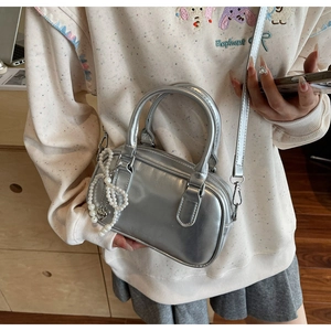 Detail of silver metallic Boston bag with faux leather finish and pearl bow charm accessory