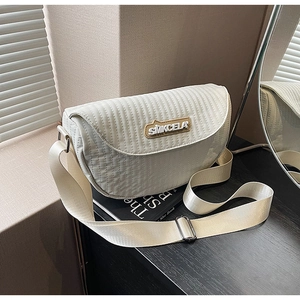 Detail of white quilted saddle bag showing vertical stitching and adjustable wide strap