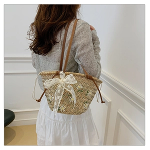 Detail of straw bucket bag with floral embroidery and white lace bow decoration