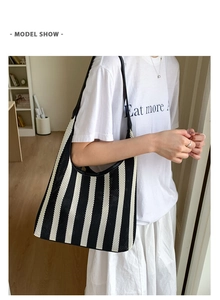 Model wearing a black and white striped woven tote bag with leather shoulder straps