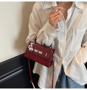 Detail of dark red patent leather handbag with silver clasp and spherical pendant