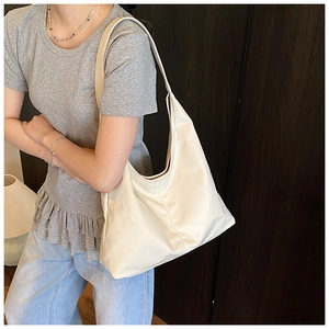 Side view of a beige high-capacity hobo bag worn by a model in a cozy interior setting