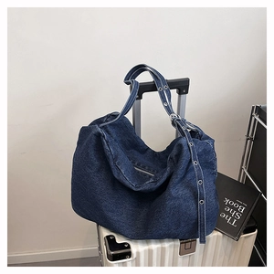 Detail of deep blue denim tote bag with metallic eyelet strap and zipper closure