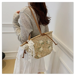 Detail of straw bucket bag with white daisy embroidery and lace bow for summer beach style