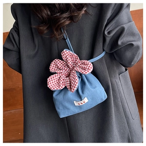 Detail of blue denim mini crossbody bag with red gingham flower drawstring and Yes Honey label