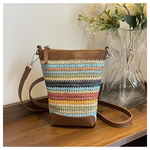 Detail of colorful woven straw texture with brown leather trim and zipper on mini bag