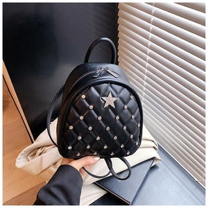 Detail of a black quilted mini backpack featuring a silver rhinestone star and studs