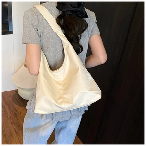 Close-up of cream nylon tote bag texture and wide shoulder strap on model back
