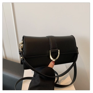 Détail d'un sac à bandoulière rectangulaire noir avec boucle dorée en fer à cheval