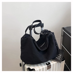 Detail view of a black canvas hobo bag with an adjustable wide strap on luggage