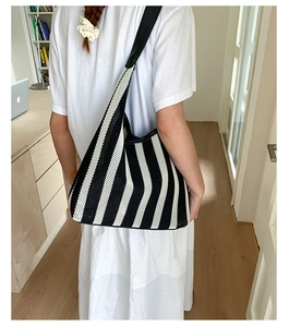 Detail of a large woven tote bag with black and white stripes and leather shoulder straps