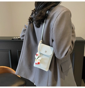 Close-up of light blue pebbled leather phone bag with a cute white duck charm detail