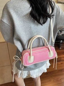 Pink and beige cylinder Boston bag with tassels shown on a model in a home setting