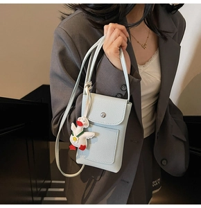 Detail of light blue lychee pattern crossbody phone bag with cute cartoon duck charm