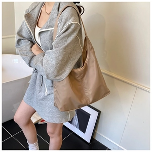 Close-up of khaki large capacity hobo bag worn by model in casual sporty style