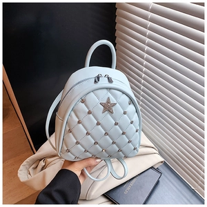Macro detail of quilted light blue mini backpack with star patch and metal rivets
