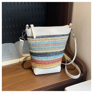 Close-up of rainbow straw woven bag with white leather strap on a wooden shelf