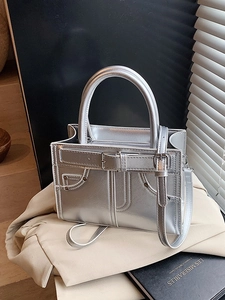Sac à main argenté métallisé avec lanières à boucles et rivets sur surface stylée