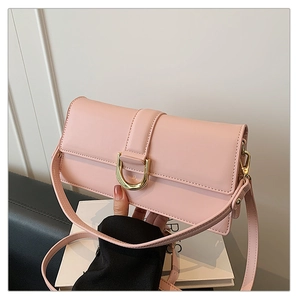 Détail d'un sac à bandoulière en cuir rose avec une boucle en métal doré en forme de D