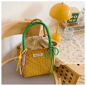 Close-up of woven straw bucket bag with green handles and purple knot details