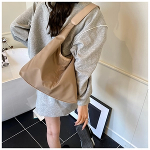 Brown hobo bag shown worn by model in a minimalist modern indoor setting
