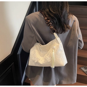 Détail du sac cabas en dentelle blanche avec broderie papillon 3D et perles en bois