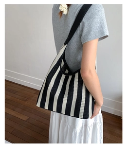Detail view of woven black and white striped tote bag with elegant long shoulder strap